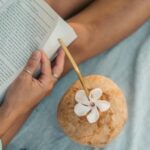 someone reading on the beach with a coconut drink