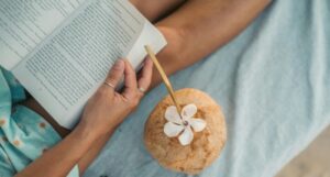 someone reading on the beach with a coconut drink