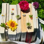 a tote bag full of books and flowers on grass