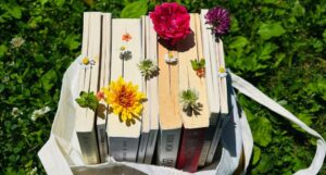 a tote bag full of books and flowers on grass