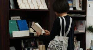 a fair-skinned older person reading a book in a bookstore