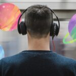 a person listening to headphones with watercolor planets around them