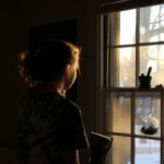 a girl looking out a window partially in silhouette