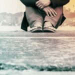 gray image of feet in flip flops. The person looks to be sitting on the ground.