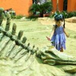 Image of an Asian child in front of a dinosaur skeleton