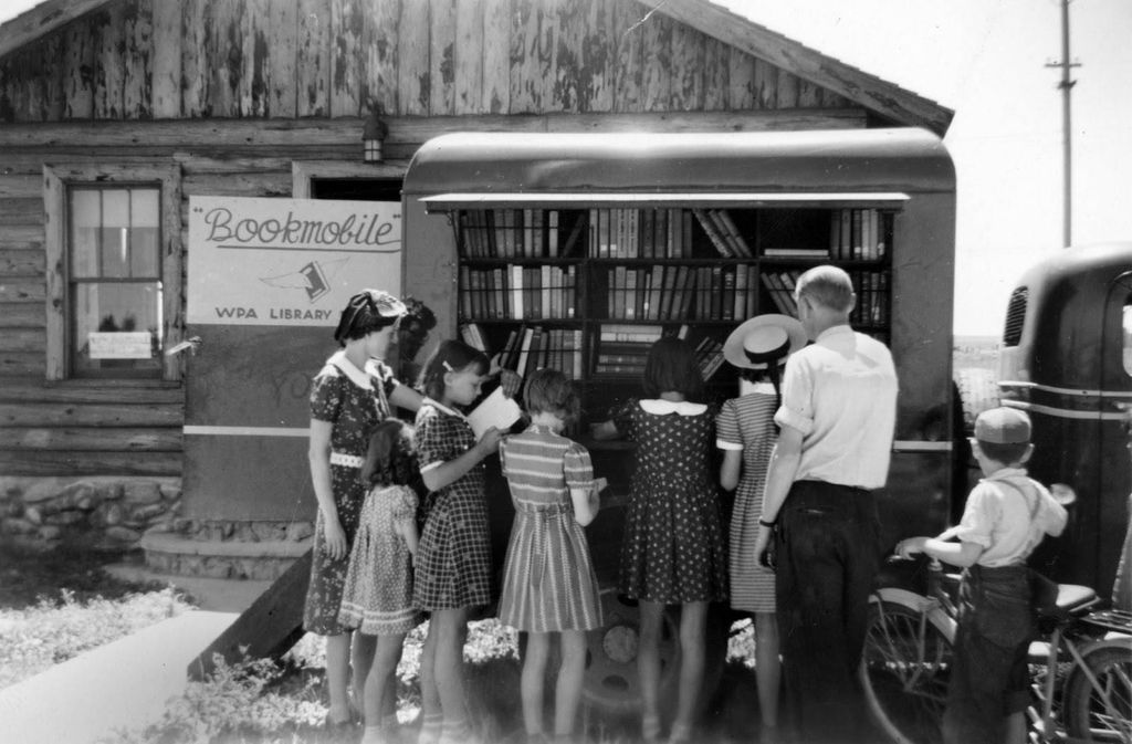 Children browse the exterior shelves of a bookmobile
