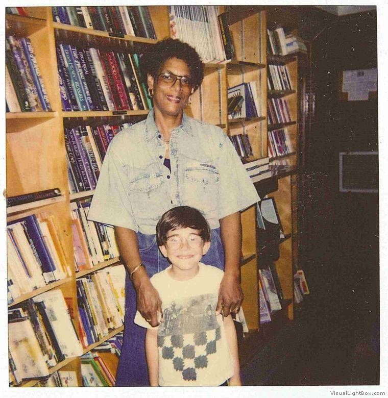 woman and child posed in front of bookmobile interior shelves