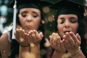 image of two new high school graduates in graduation regalia