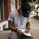 Man writing with left hand in a notebook on his lap