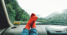 Feet on car dashboard with forest background