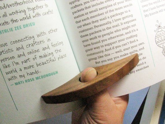 Wooden ring on a reader's finger, holding book open