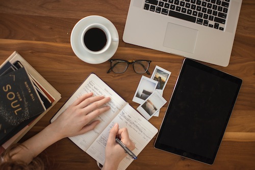 Photo of computer, books, and notebooks on table