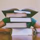 Person crouches behind a pile of books.