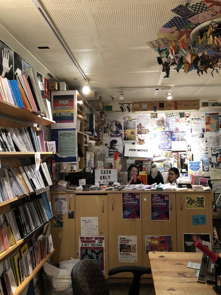 Shop counter staffed by two women, surrounded by publications