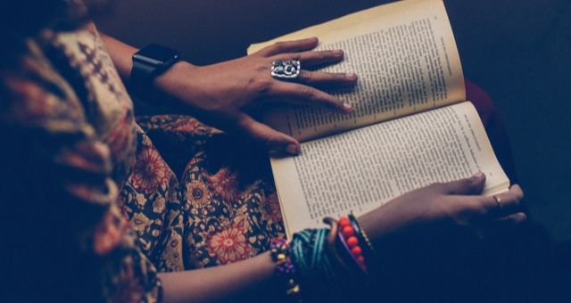 A book being read, with one hand on the page