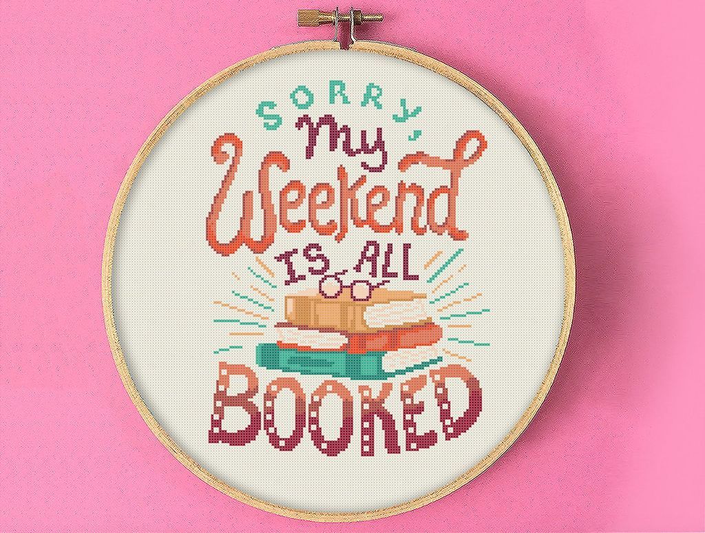 Cross stitch of "Sorry, my weekend is all booked" with a pile of books
