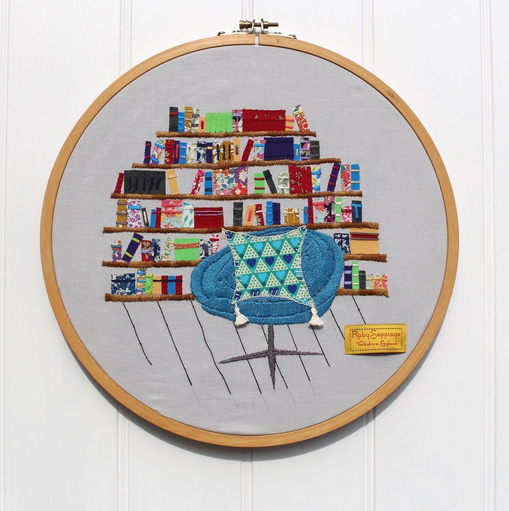 Embroidery of a reading chair in front of a full book shelf