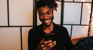a photo of a Black man holding a phone and smiling