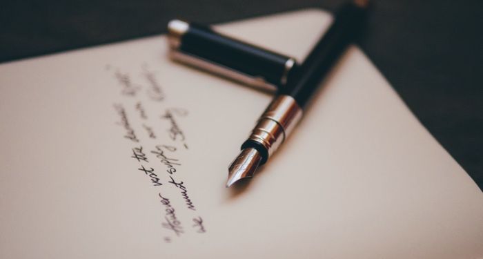a fountain pen resting on a page with a few lines of cursive text