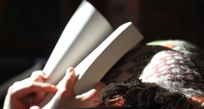 image of hands holding a book while resting on a blanket https://unsplash.com/photos/xZiHAa09Jcs