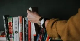 a hand selecting a book of a shelf