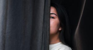 woman peeking out from behind a curtain