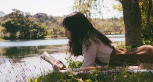 a young Asian woman reading outside