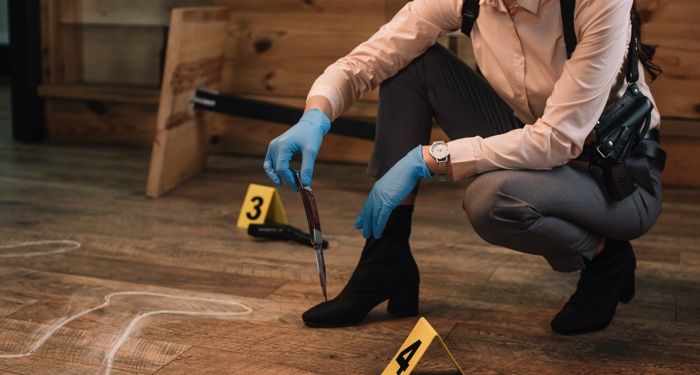 a photo of someone at a crime scene picking up a knife with gloved hands