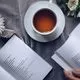 a cup of tea and flowers arranged next to two open books of poetry