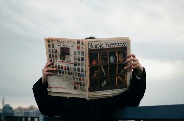 How to Write a Professional Book Review l BookRiot.com (Source: https://www.pexels.com/photo/person-holding-white-and-brown-newspaper-3957616/)