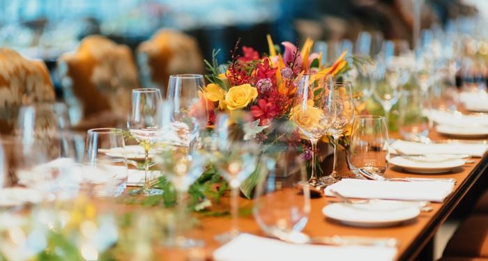 a long table set with glassware, white dinnerware, and flowers