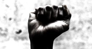black and white image of a hand with dark skin raised in a fist