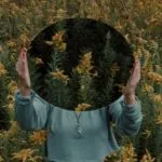 a photo of a woman holding a mirror in a forest