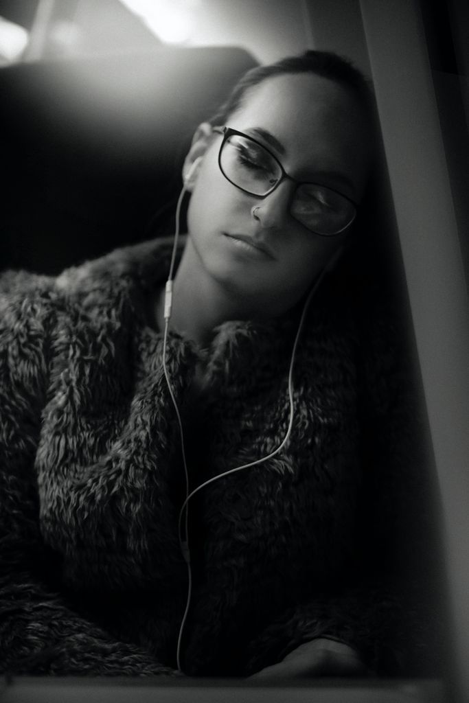 Female-presenting person sleeping with earbuds in