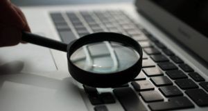 image of a magnifying glass being held over a laptop computer