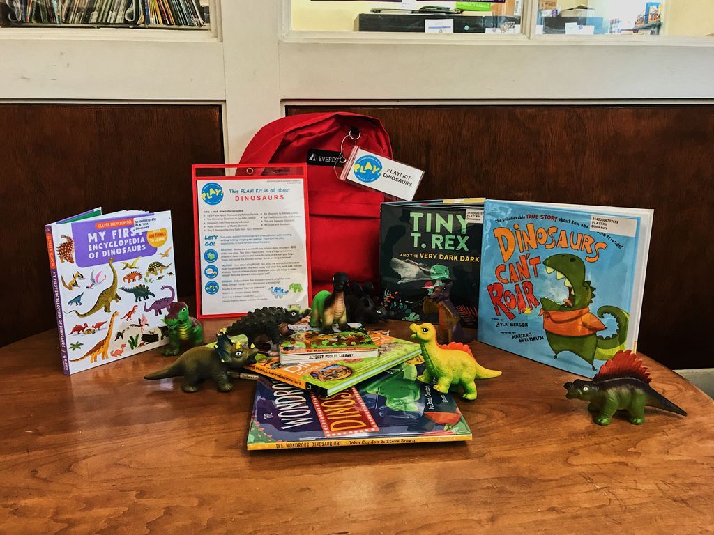 Books, dinosaur figurines, and a red backpack