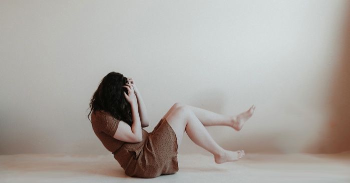 woman in a brown dress holding her head