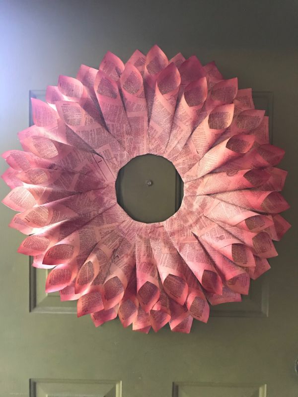 A picture of a book page wreath spray painted red hanging on a door