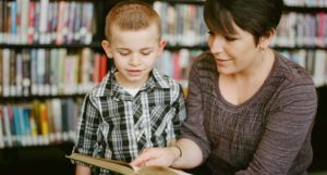 a photo of a children's librarian reading aloud in a library with a child