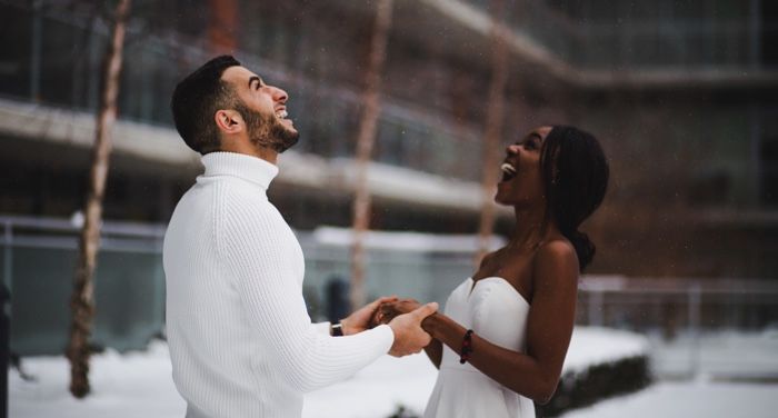 couple standing outside in the snow for winter or holiday romance