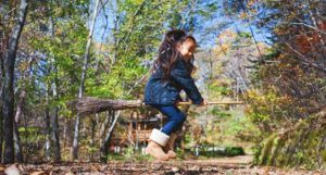 little girl child trying to fly on broomstick outside