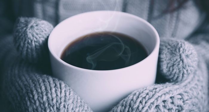 mittened hands holding coffee cup for cozy winter