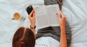 image of a woman reading in bed with cell phone and coffee
