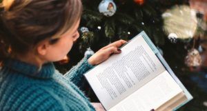 woman reading by the christmas tree for holiday