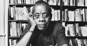 a photo of James Baldwin with bookshelves in the background