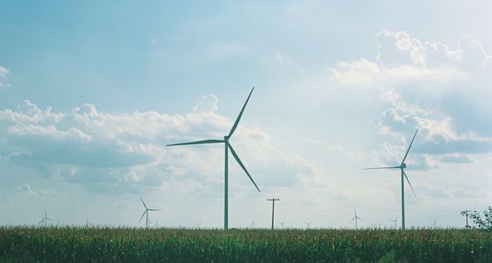 wind vanes above a grass field against blue sky