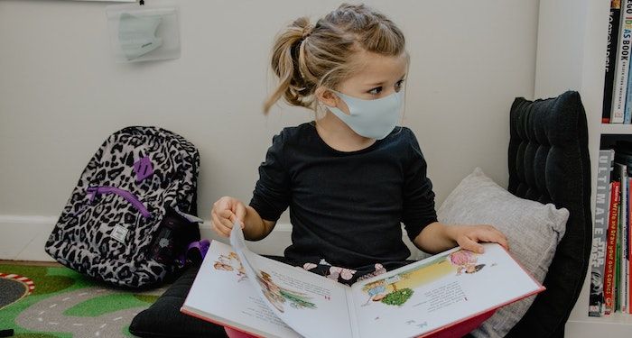 child wearing mask reading a picture book