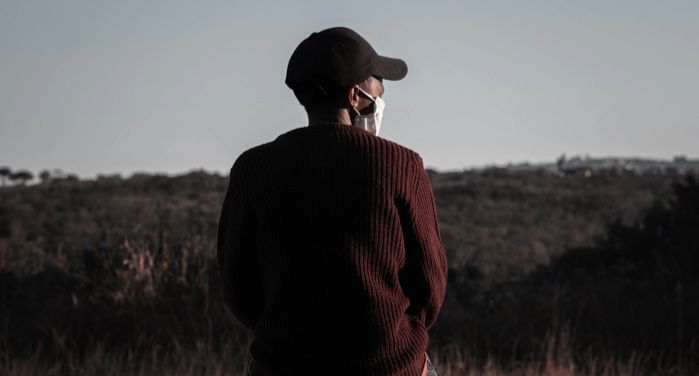 image from behind of a man in black baseball cap and dark red sweater wearing a face mask https://unsplash.com/photos/VtvQ4RcFE08