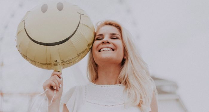 image of a woman smiling and holding up a smiley face balloon https://www.pexels.com/photo/woman-holding-a-smiley-balloon-1236678/