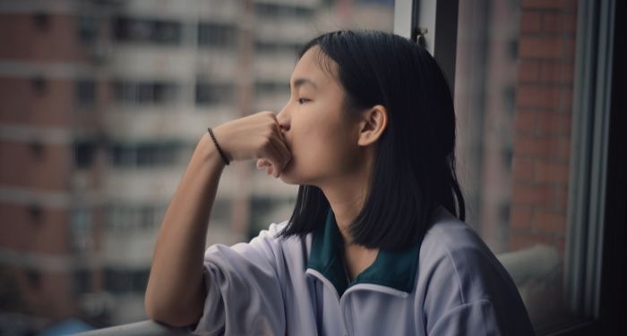 teen or young woman looking out the window thinking